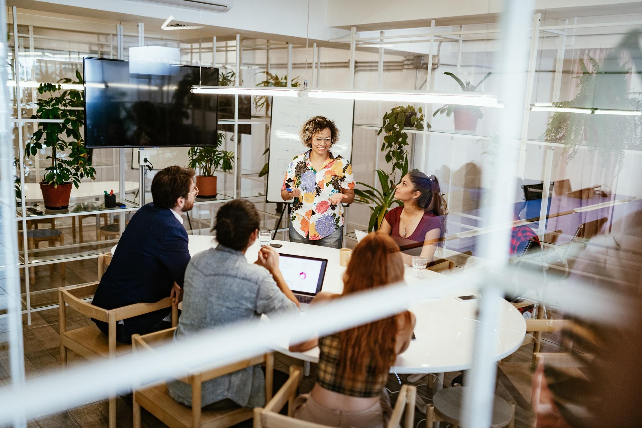 A group of smiling people sitting around a table in a brightly lit office.